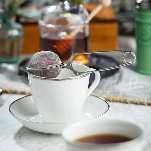 White teacup with a tea infuser on a marble surface with a blurred background