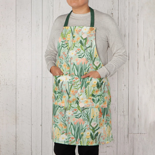 Person wearing a floral apron against a wooden background