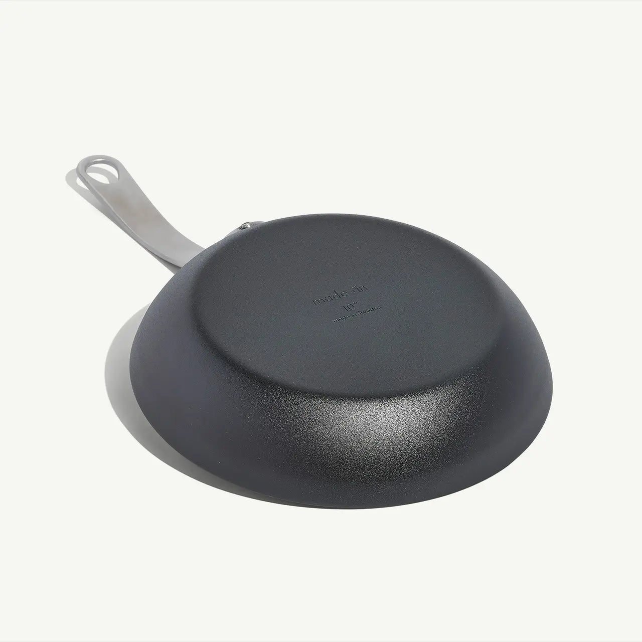 A black carbon steel frying pan with a stainless steel handle, pre-seasoned and ready for cooking on a white background.