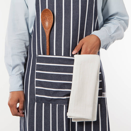 Person wearing a striped apron with a wooden spoon and white towel in the pocket on a white background