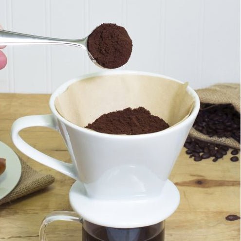 Coffee brewing process with a white pour-over coffee maker on a wooden surface.