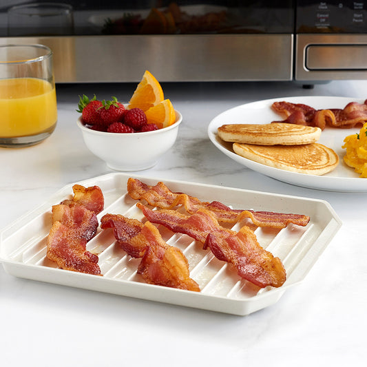 Tray of bacon on a kitchen counter with breakfast items in the background