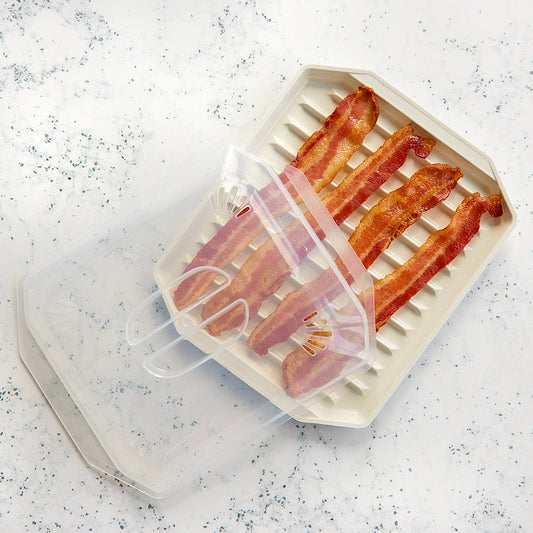 Bacon slices on a white grill pan with a transparent lid on a speckled countertop.