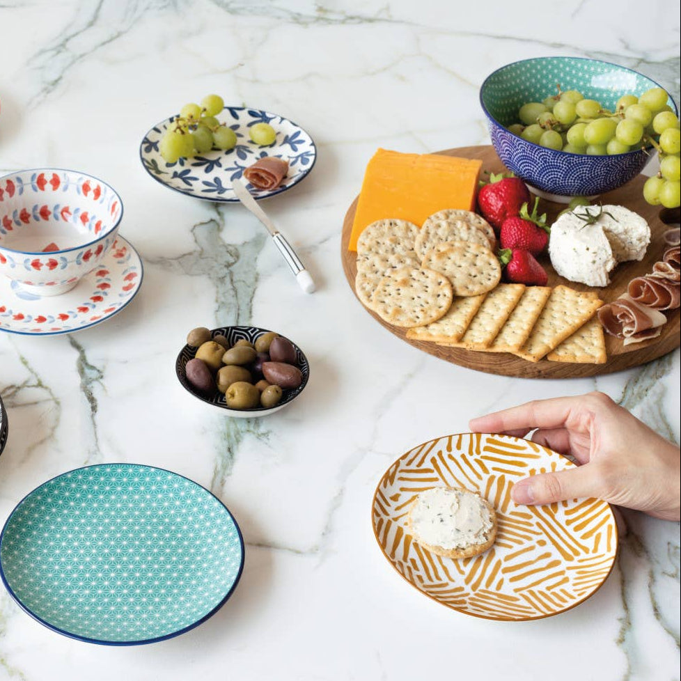Colorful ceramic plates with various food items on a marble surface