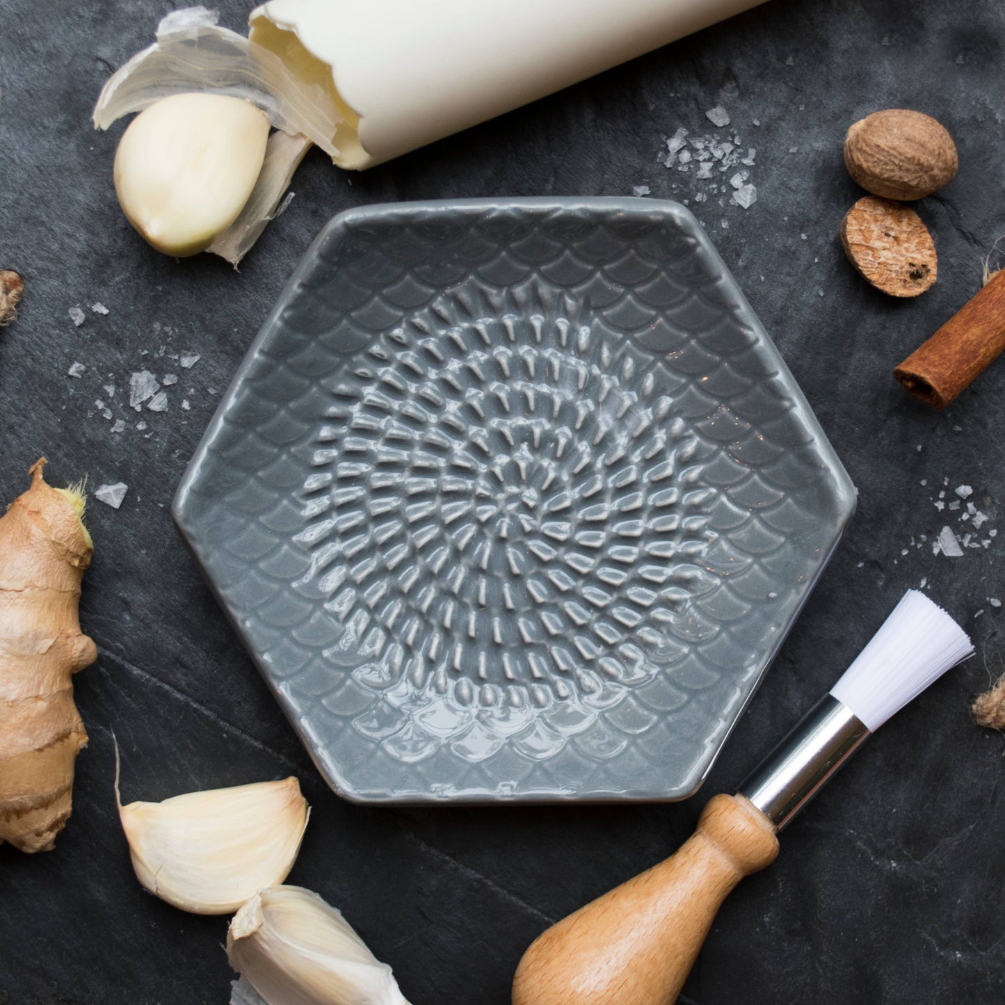 The Grate Plate is a ceramic grating plate used to grate garlic, ginger, peppers, nutmeg, chocolate, hard cheeses and much more! Perfect for adding fresh flavor to any dish. It's easy to clean and can be reused for an endless variety of culinary creations. Plus, the handy silicone garlic peeler and gathering brush make prepping fast and mess-free!