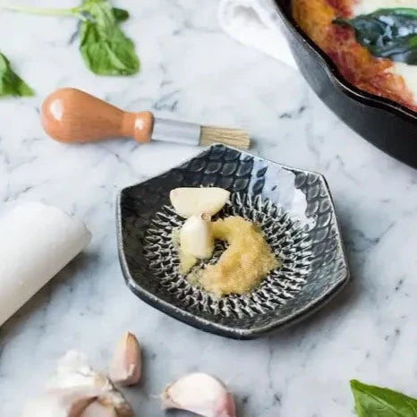 The Grate Plate is a ceramic grating plate used to grate garlic, ginger, peppers, nutmeg, chocolate, hard cheeses and much more! Perfect for adding fresh flavor to any dish. It's easy to clean and can be reused for an endless variety of culinary creations. Plus, the handy silicone garlic peeler and gathering brush make prepping fast and mess-free!