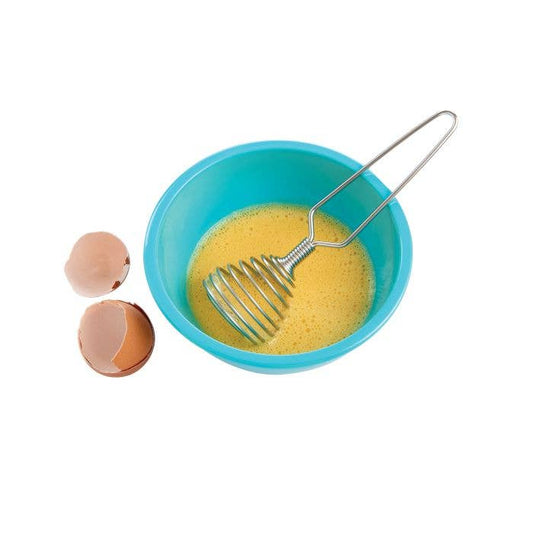 Blue bowl with whisked eggs and a whisk, next to two eggshells on a white background
