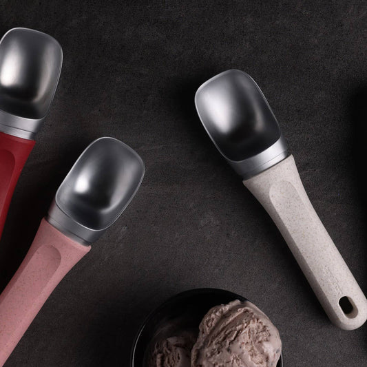 Five ice cream scoops with different handles on a dark surface.