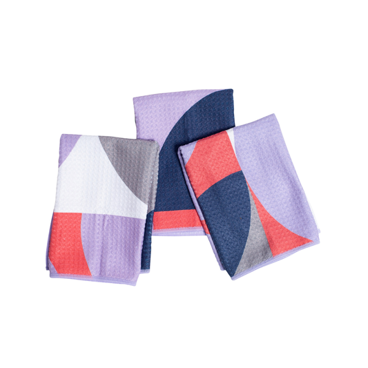 Set of three geometric-patterned napkins in purple, blue, and red on a white background