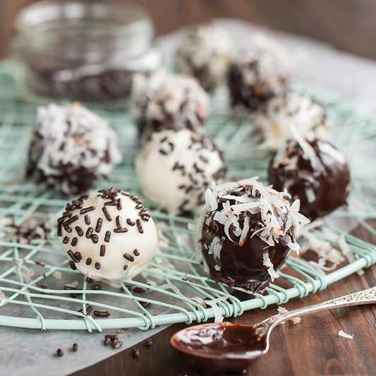 Chocolate truffles with coconut and sprinkles on a cooling rack.