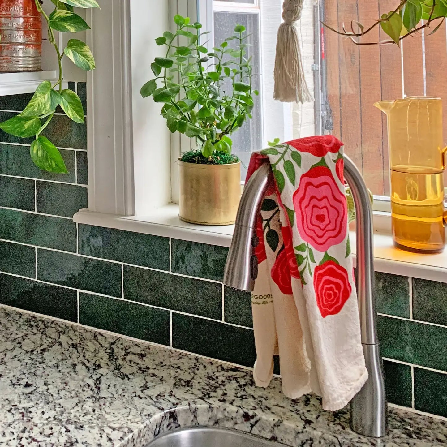 Featuring vibrant pink and red roses in a delightful pink jug, this towel is the perfect way to brighten your kitchen and make everyday tasks a little more cheerful.