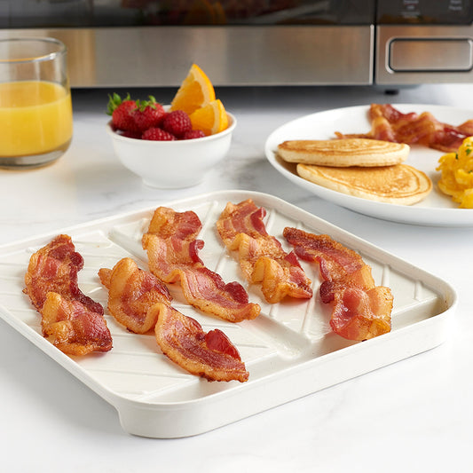 Bacon on a white tray with breakfast items in the background