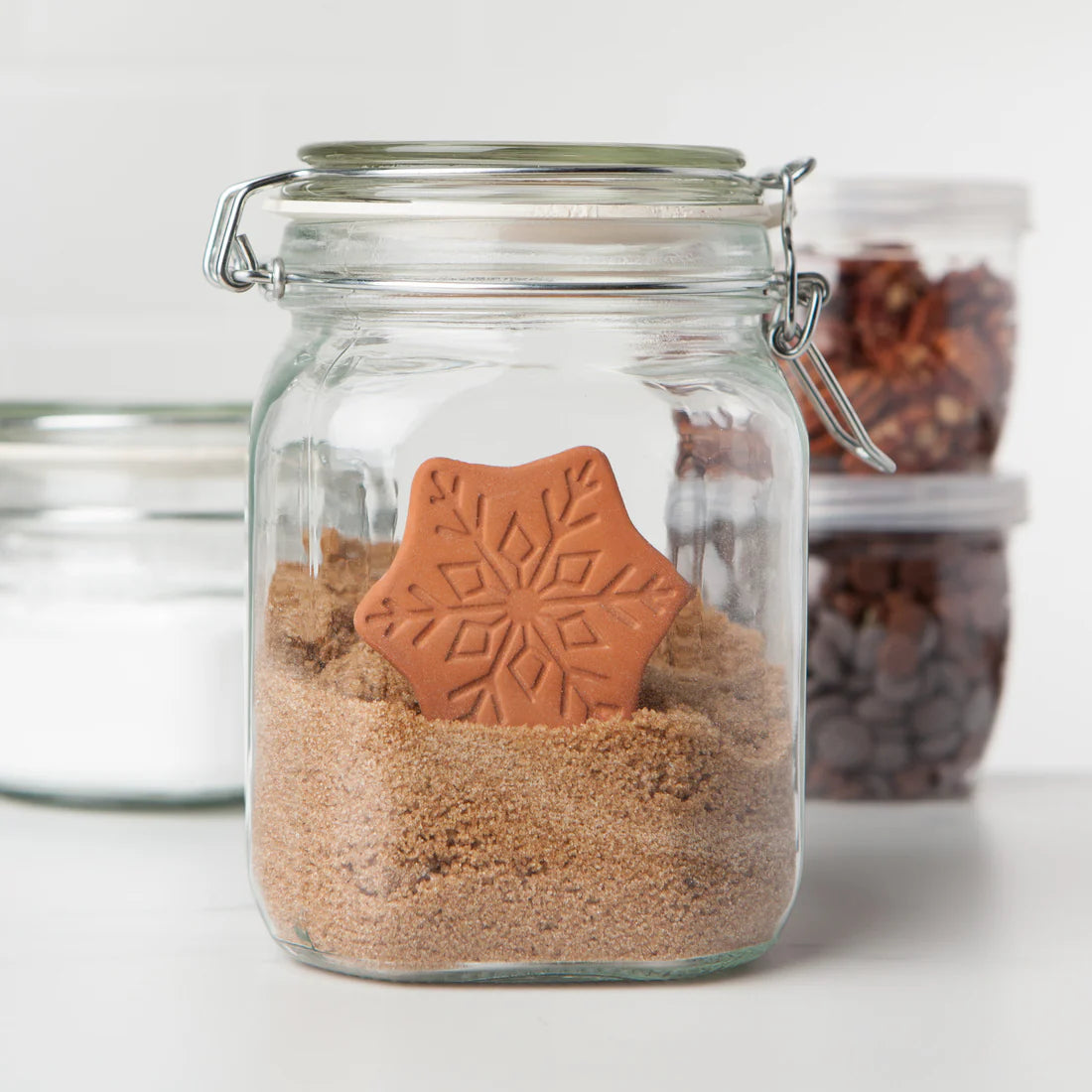 Glass jar with brown sugar and a star-shaped cookie on a white background