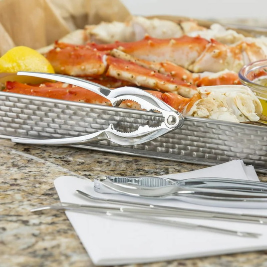 Metallic crab Crackers on a table with crab legs and utensils