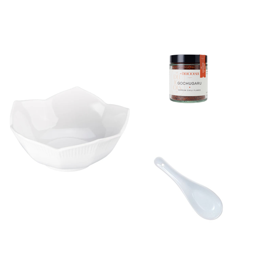 White bowl, white spoon, and container labeled 'Gochugaru' on a white background