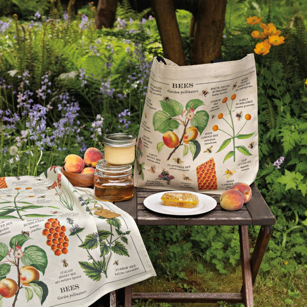 Table with botanical-themed towels, food, and a candle in a garden setting