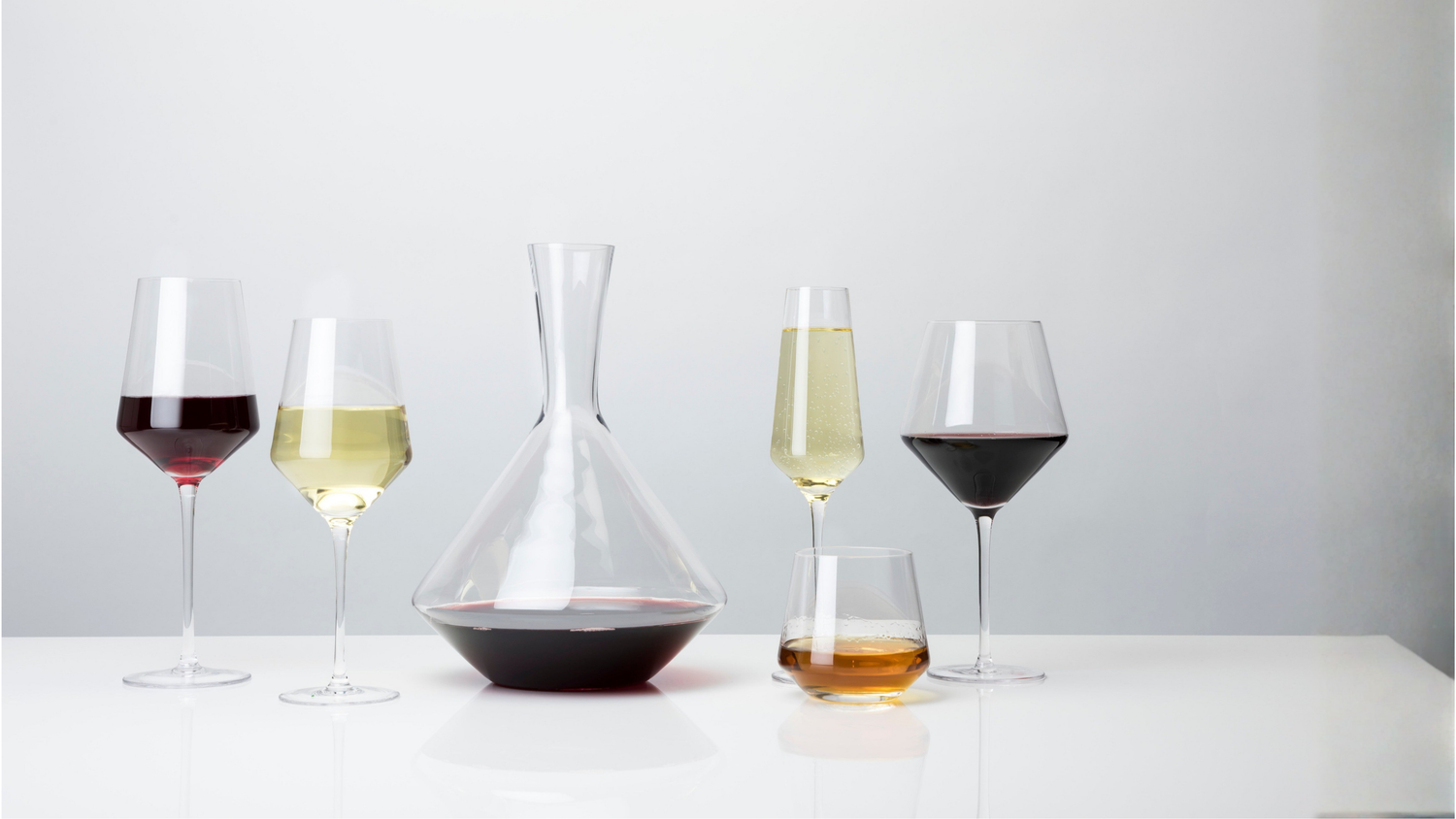 Wine glasses with different types of wine on a white surface