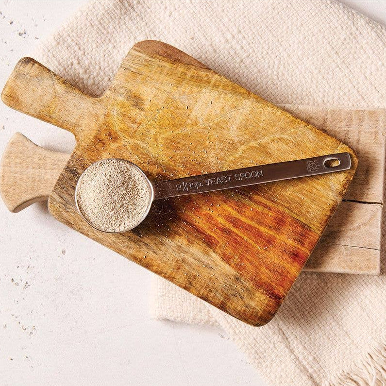 Wooden cutting board with a measuring cup on a light surface
