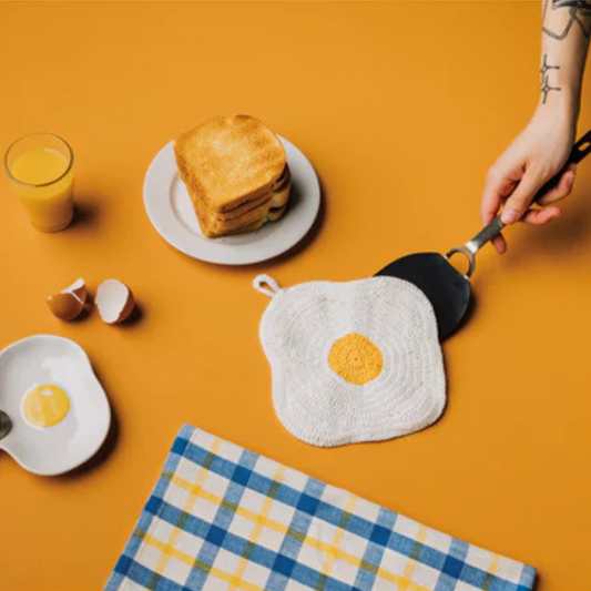 Add a playful touch to your kitchen with the Crochet Egg Trivet, a delightful blend of fun and function. Handmade with care, this 100% cotton trivet is inspired by our joyful collections, bringing warmth and personality to your cooking space.