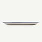 A long, shallow oval plate in warm off-white with a thin dark blue rim, shown from a side profile against a solid off-white background.
