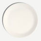 A plain white ceramic plate shown from a top-down view against a light gray background.