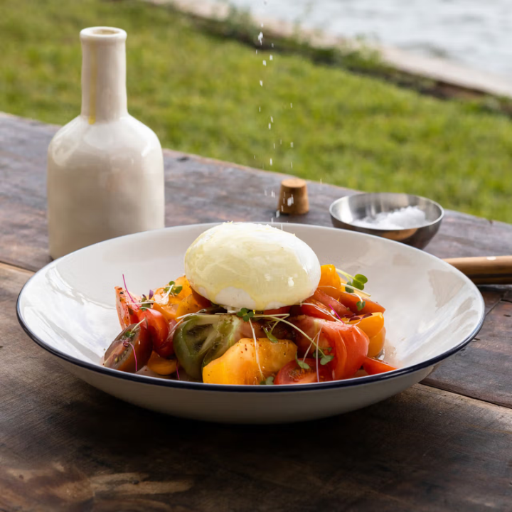 Bowl of salad with a poached egg on a wooden table outdoors