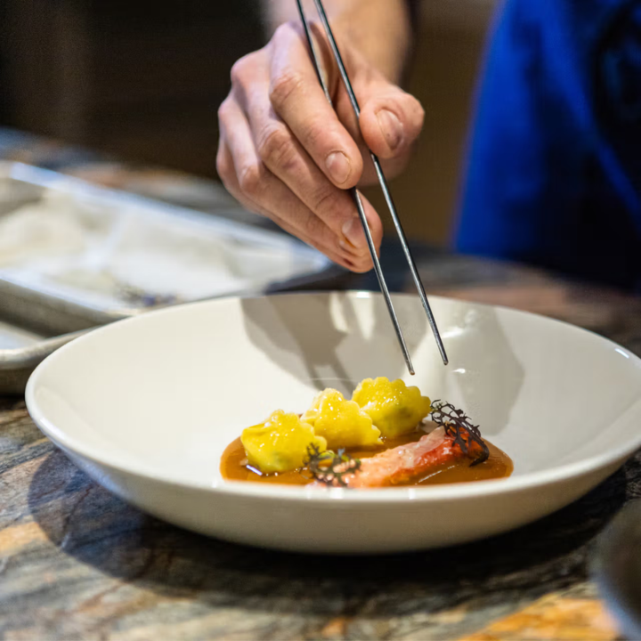 Person using chopsticks to eat from a bowl on a table