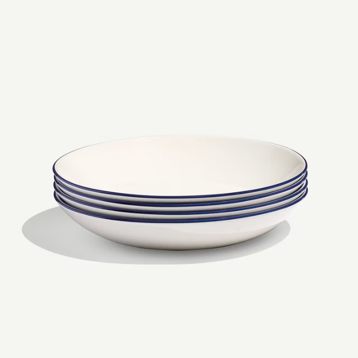 A stack of five white ceramic bowls with a thin dark blue rim, photographed on a clean off-white background with a soft shadow.
