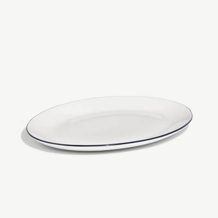 White oval plate with a thin black rim on a white background