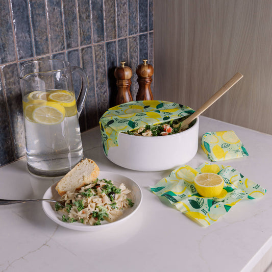 Kitchen counter with a bowl of salad, a glass of water with lemon slices, and a pot with a lid on a countertop.
