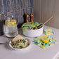 Kitchen counter with a bowl of salad, a glass of water with lemon slices, and a pot with a lid on a countertop.