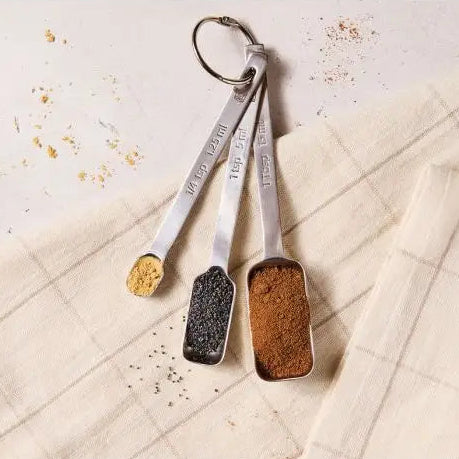 Set of measuring spoons with spices on a textured surface