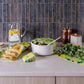 Kitchen counter with reusable food wraps, a bowl of salad, and kitchen items against a tiled wall.