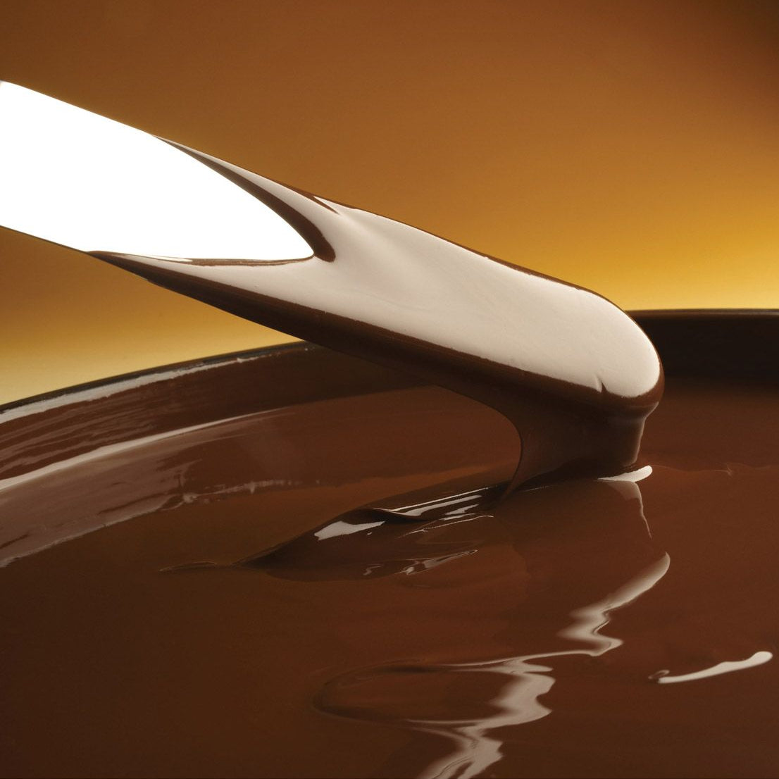 Close-up of a spoon with melted chocolate on a brown background
