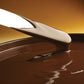 Close-up of a spoon with melted chocolate on a brown background
