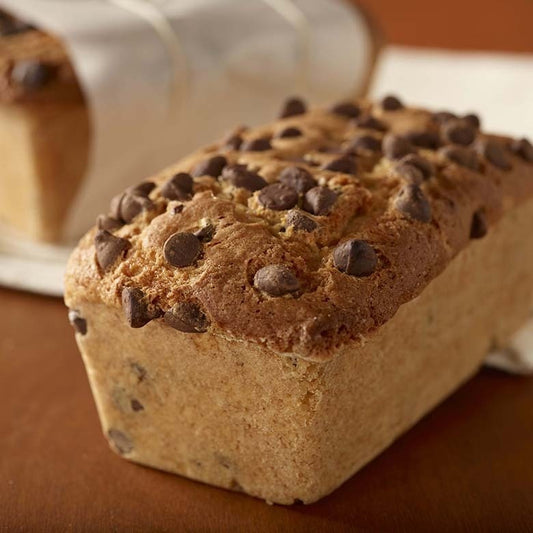Loaf of chocolate chip bread on a wooden surface with a blurred background