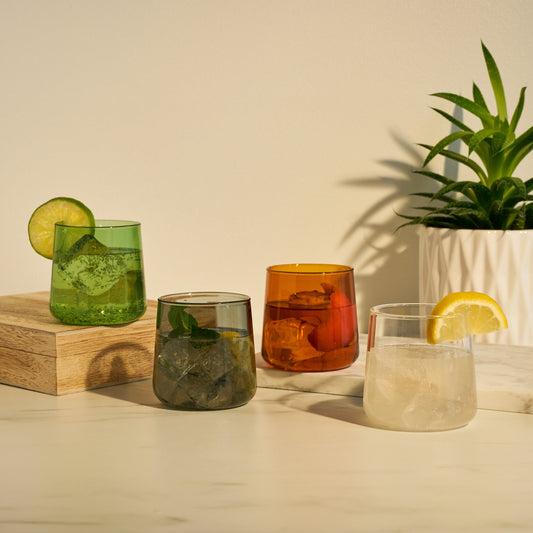 Handcrafted from durable glass and tinted with natural minerals, this set of multicolored cocktail glasses in muted jewel tones brings a pop of color to your glassware collection. Suitable for cocktails, wine, or iced coffee, each stemless wine glass holds 10.5 oz. and is dishwasher safe.  Handmade from sturdy borosilicate glass, these high quality colored wine glasses are dishwasher safe and made to last. The modern, slightly tapered shape keeps the focus on the curated color selection.
