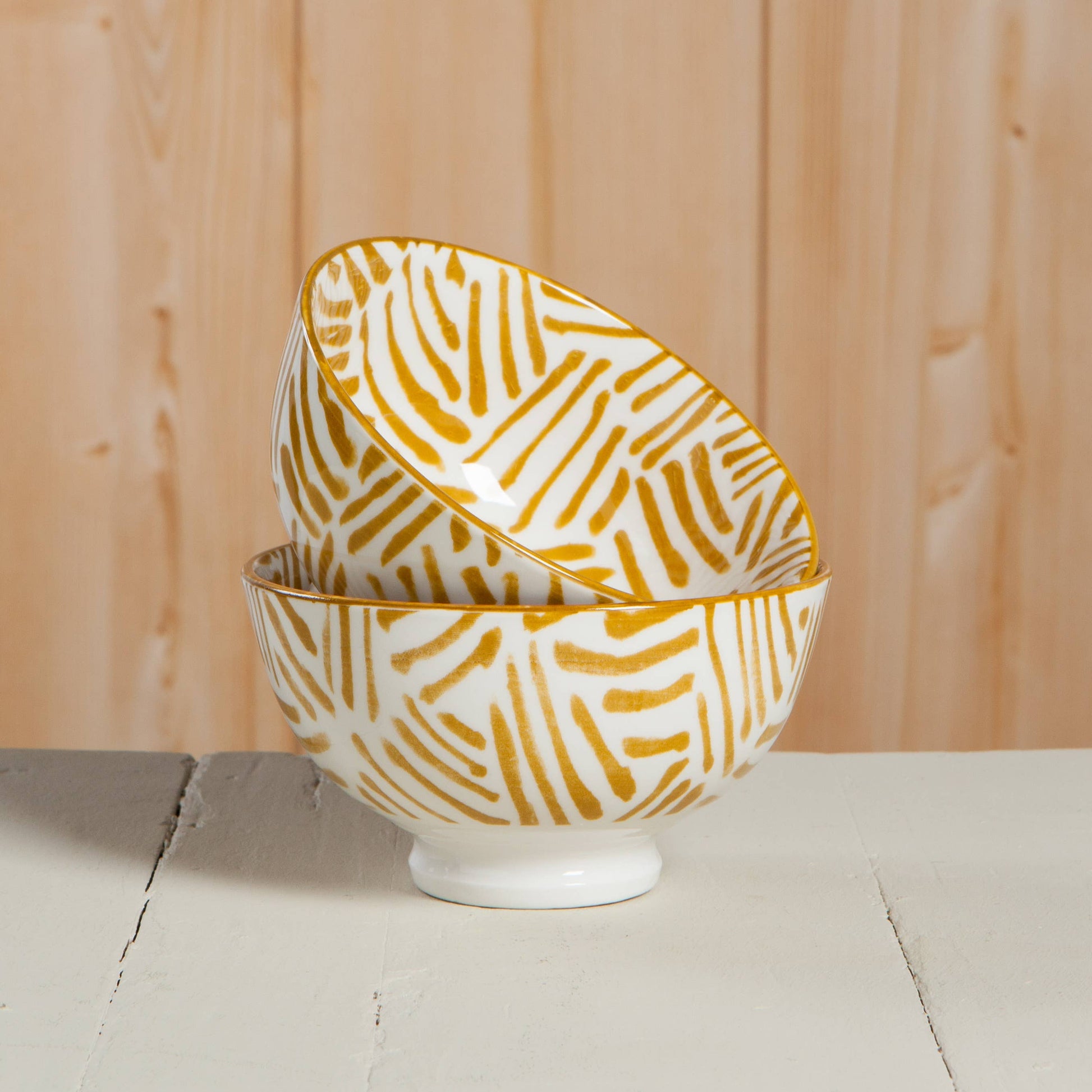 Two ceramic bowls with gold patterns on a wooden surface