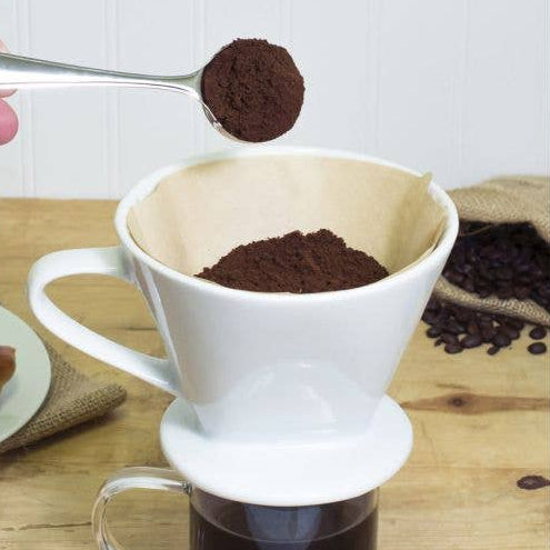 Coffee brewing process with a white pour-over coffee maker on a wooden surface.