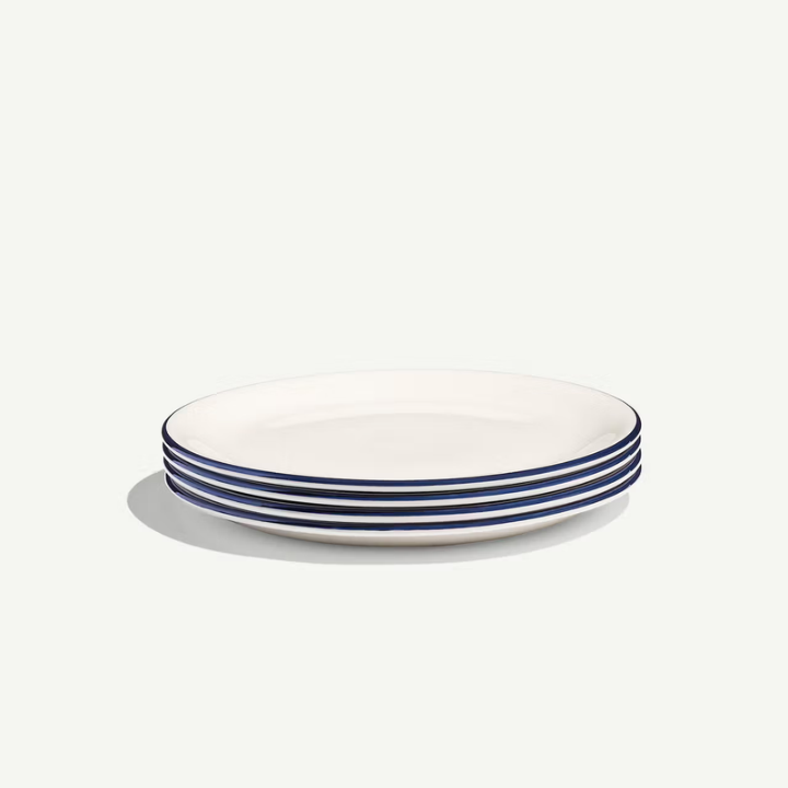 A stack of five round white ceramic plates with thin dark blue stripes along the rims, set against a clean off-white background.