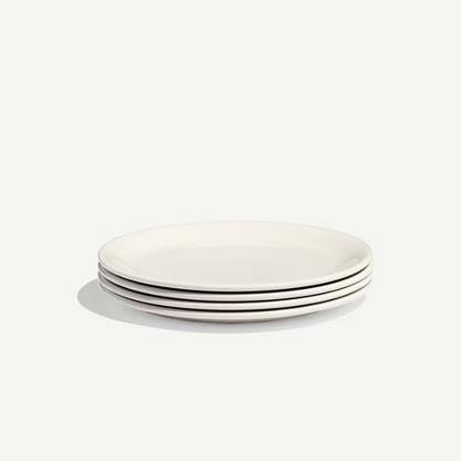 A stack of five plain white ceramic plates with a subtle drop shadow on a light off-white background.