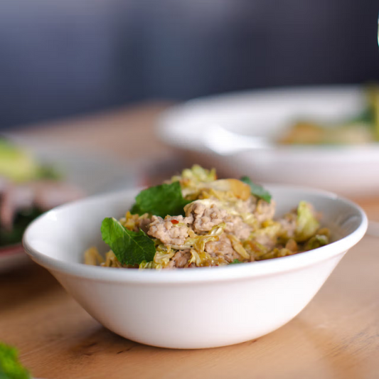 White bowl with a serving of food on a wooden surface