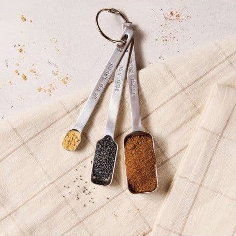 Set of four measuring spoons with spices on a textured surface