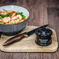 Knife sharpener on a wooden cutting board with a bowl of shrimp and vegetables in the background.