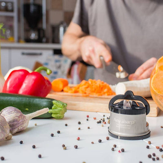 Person preparing vegetables with a knife sharpener on a kitchen counter