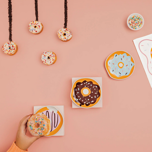 Donut plastes being used with donuts on a pink table. 