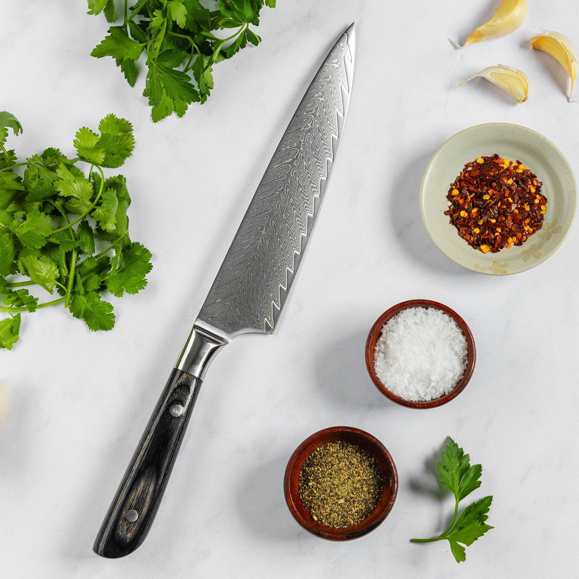 Knife on white surface with spices and herbs. 