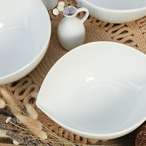 Set of white ceramic bowls on a textured surface with decorative elements.