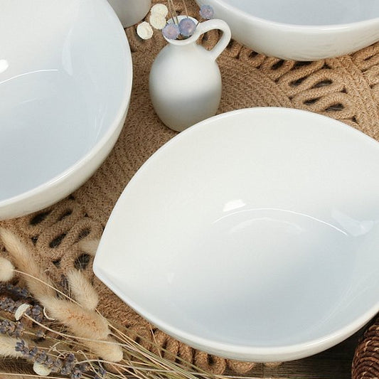 Set of white ceramic bowls on a textured surface with decorative elements.
