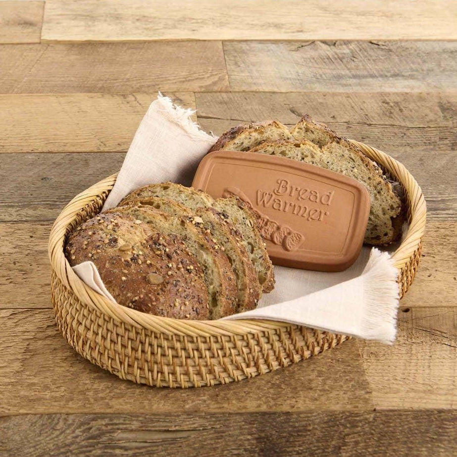 Bread in a woven basket with a bread warmer on a wooden surface